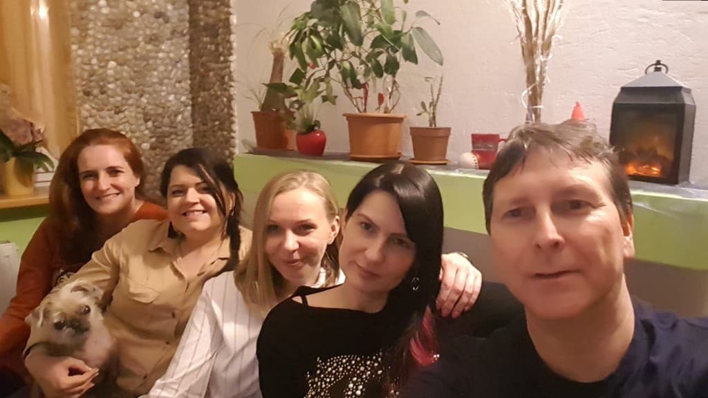 Skupinové selfie, päť ľudí a malý psík v interiéri.