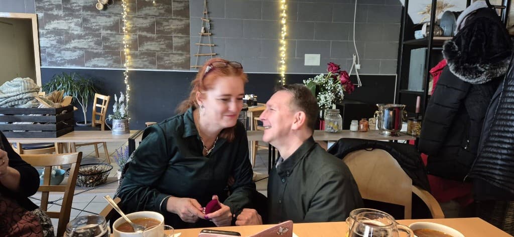 Pár pri stole s polievkou, žena drží otvorenú fialovú krabičku na prsteň.